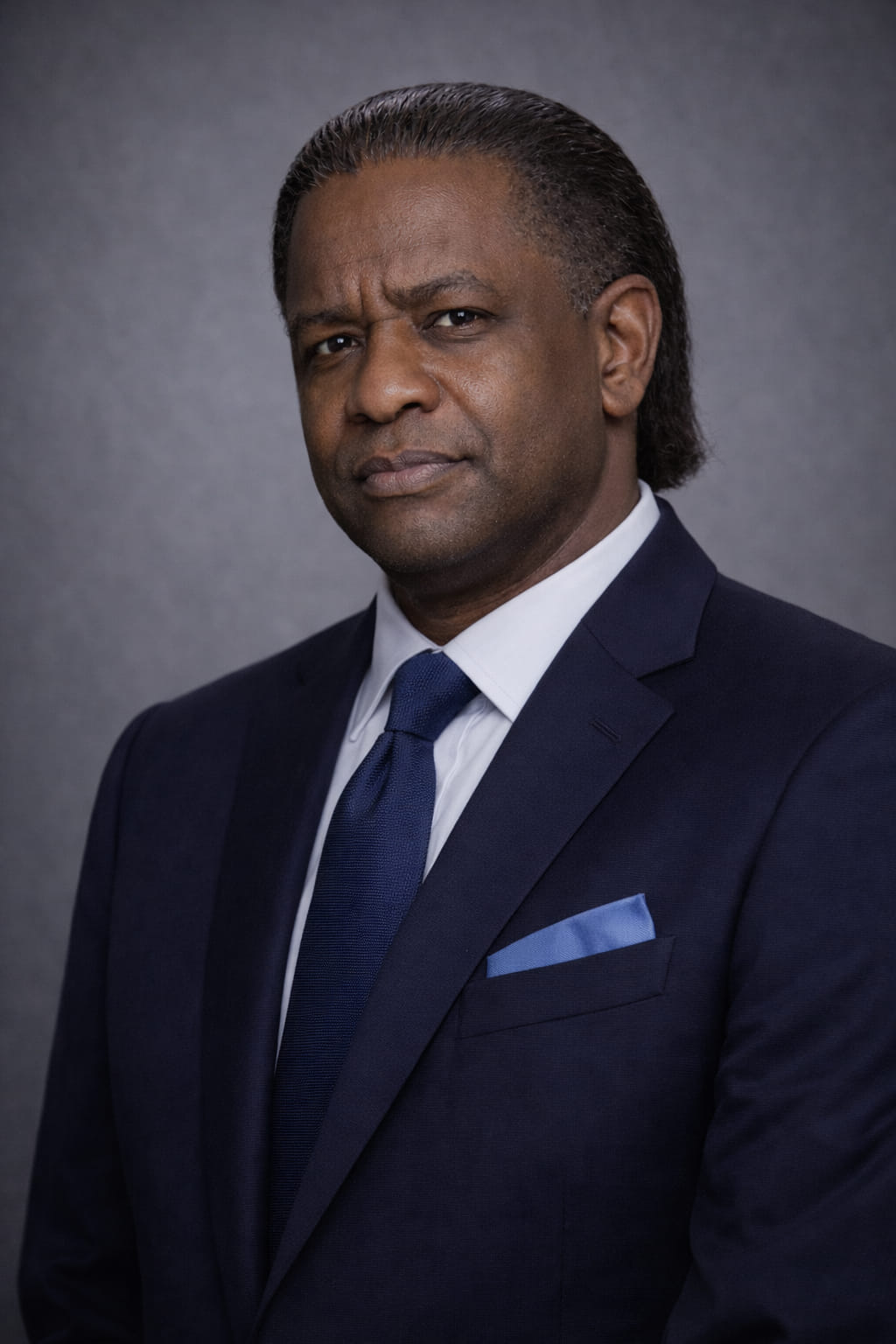 Formal portrait of a man in a dark suit and red patterned tie.